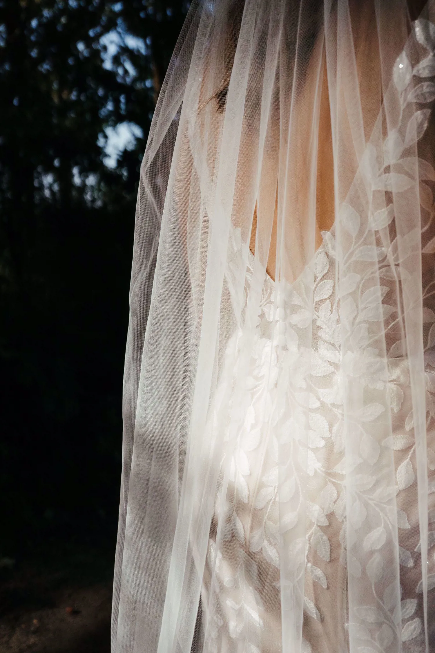 Real bride Lisa van Dooren close-up van de rug, in een romantische fit & flare jurk met bladkant en sluier.