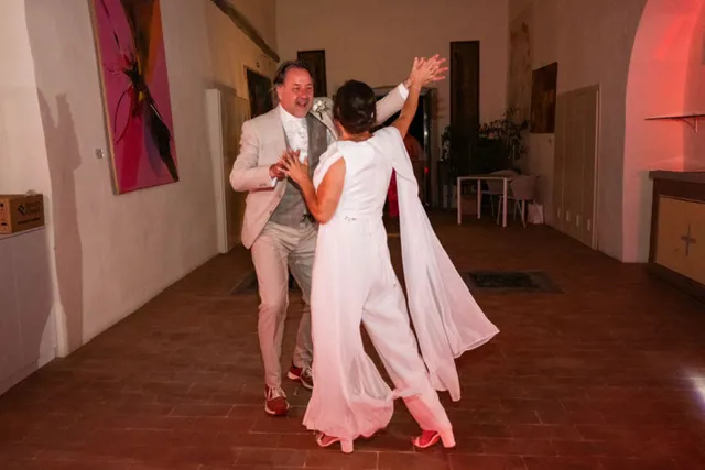 real-bride-review-daphne-de-laat-bruidshuis-diana – bruid Daphne de Laat danst samen met haar bruidegom tijdens het feest, haar soepel vallende jumpsuit met cape beweegt sierlijk mee