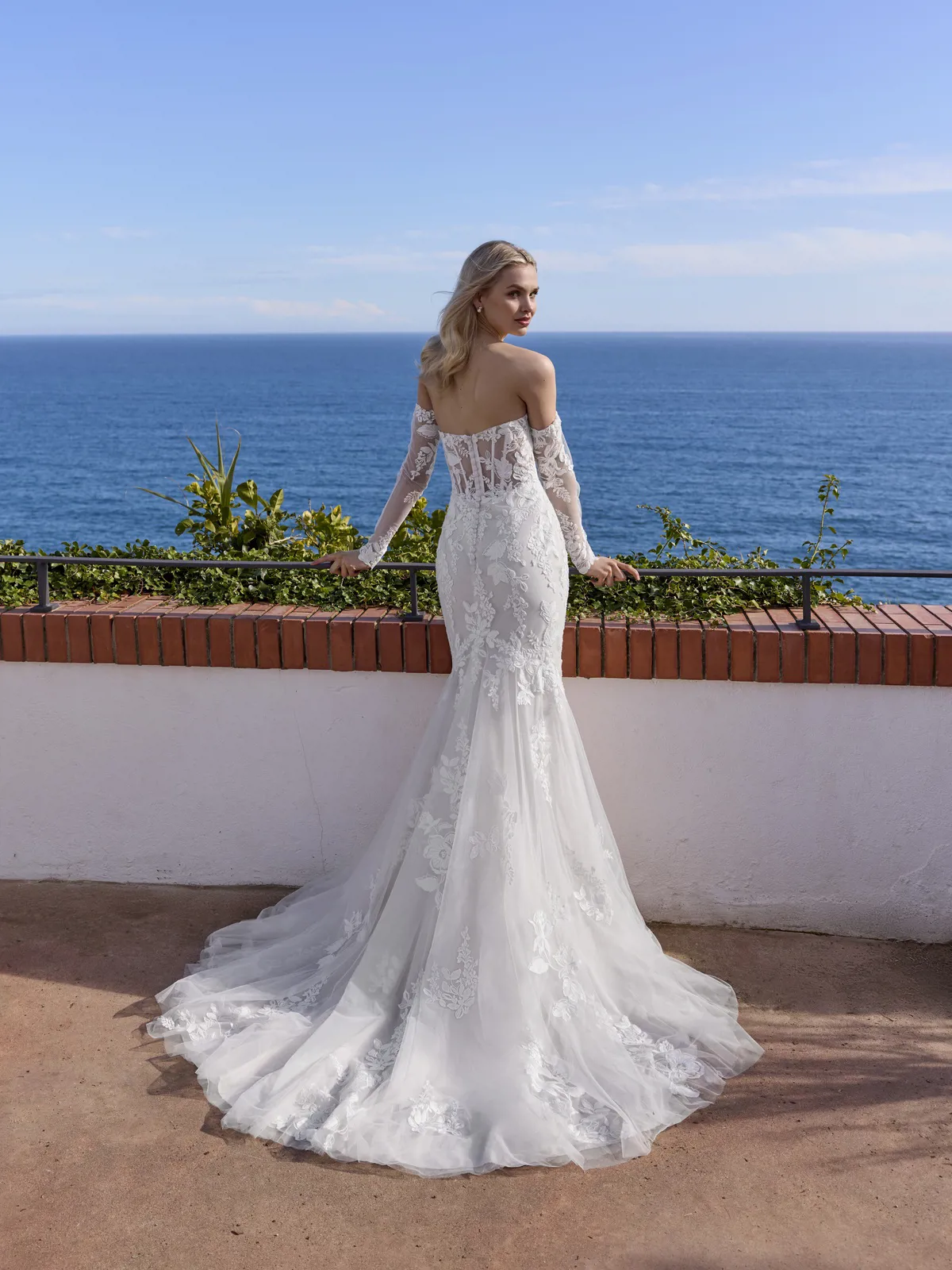 Zeemeermin trouwjurk Kisa van White one, achteraanzicht met off-shoulder kanten mouwen en see-through korsetlijfje.