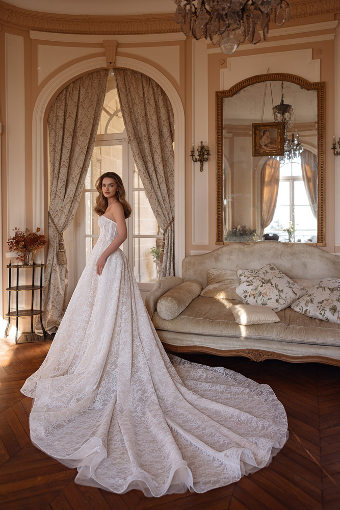 A-lijn trouwjurk met kant Maris van Justin Alexander Signature. Zijaanzicht van strapless korsetlijfje en lange sleep.