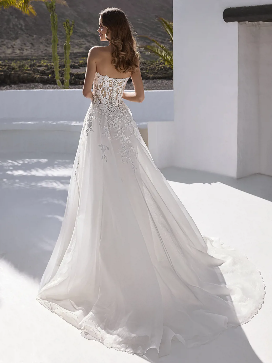 A-lijn trouwjurk Everly van Love by Enzoani. Achteraanzicht van het kanten see-through korsetlijfje en de flowy tule rok.