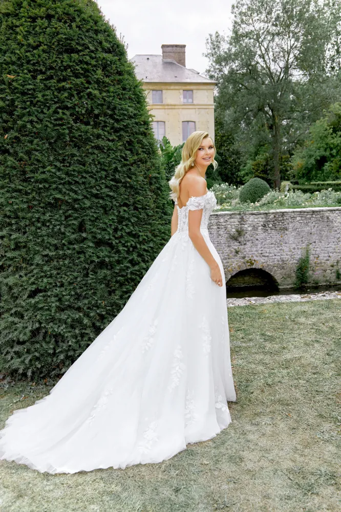Romantische A-lijn trouwjurk 44520 van Sincerity Bridal. Achteraanzicht met off-shoulder kanten mouwtjes en tule rok.