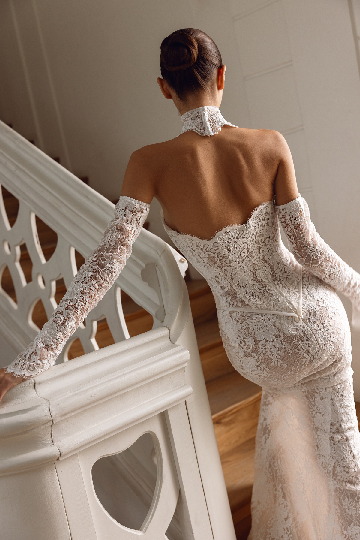 Trouwjurk met open rug Rose van Tina Valerdi. Achteraanzicht van de aangesloten kanten jurk met losse mouwen en hoge kraag.