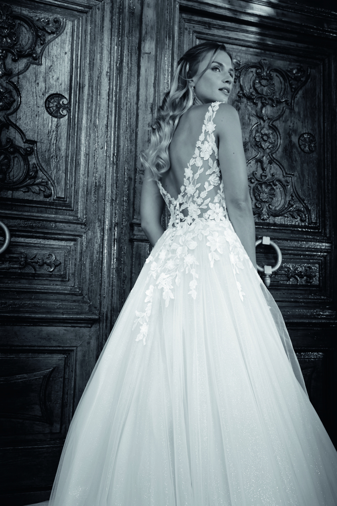 A-lijn trouwjurk Arnolda van Azuree. Achteraanzicht met diepe open rug, kanten details en een wijde glitter tule rok.