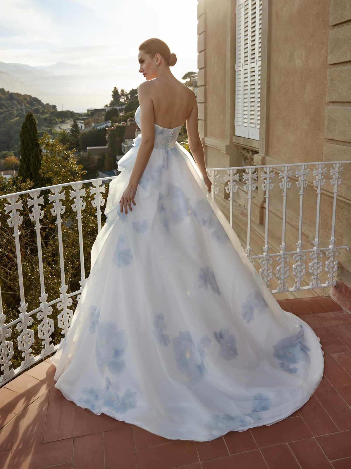 Gekleurde prinsessenjurk Gildah van San Patrick. Achteraanzicht van de strapless trouwjurk met blauwe bloemen en sleep.