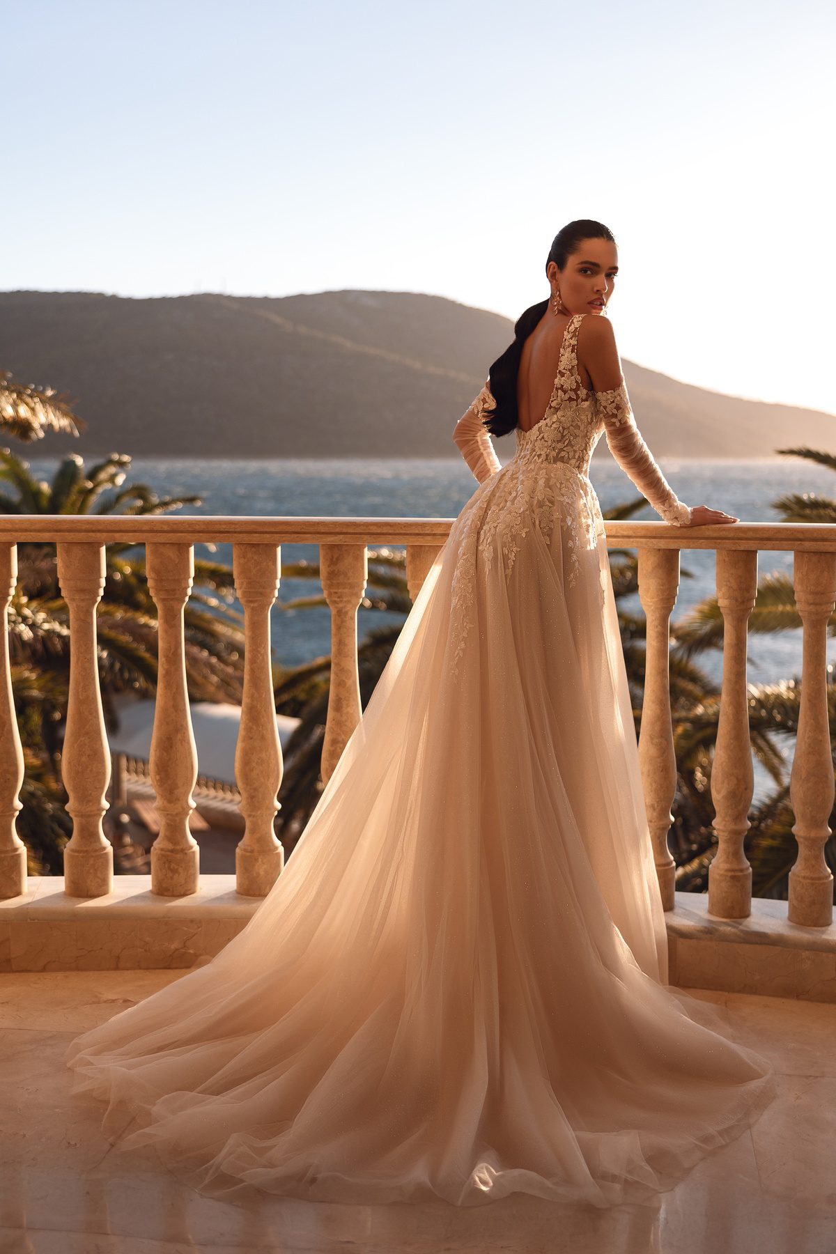 Trouwjurk met lage rug 8279 Cosmobella. Achteraanzicht van de kanten off-shoulder mouwen en de wijde, flowy tule rok.