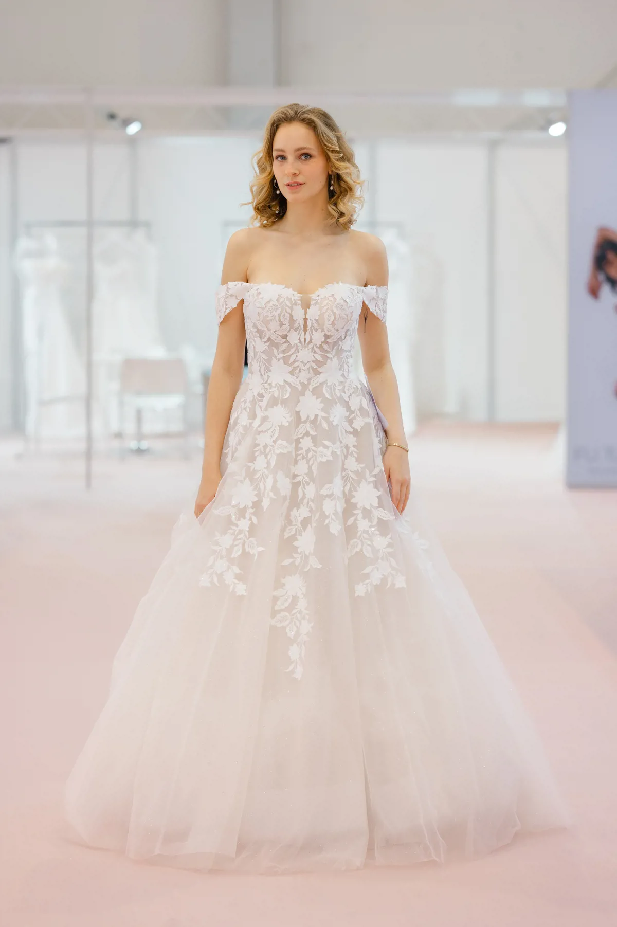Off-shoulder trouwjurk Deena van Azuree. A-lijn bruidsjurk met kanten lijfje en glitter tule rok. Vooraanzicht.