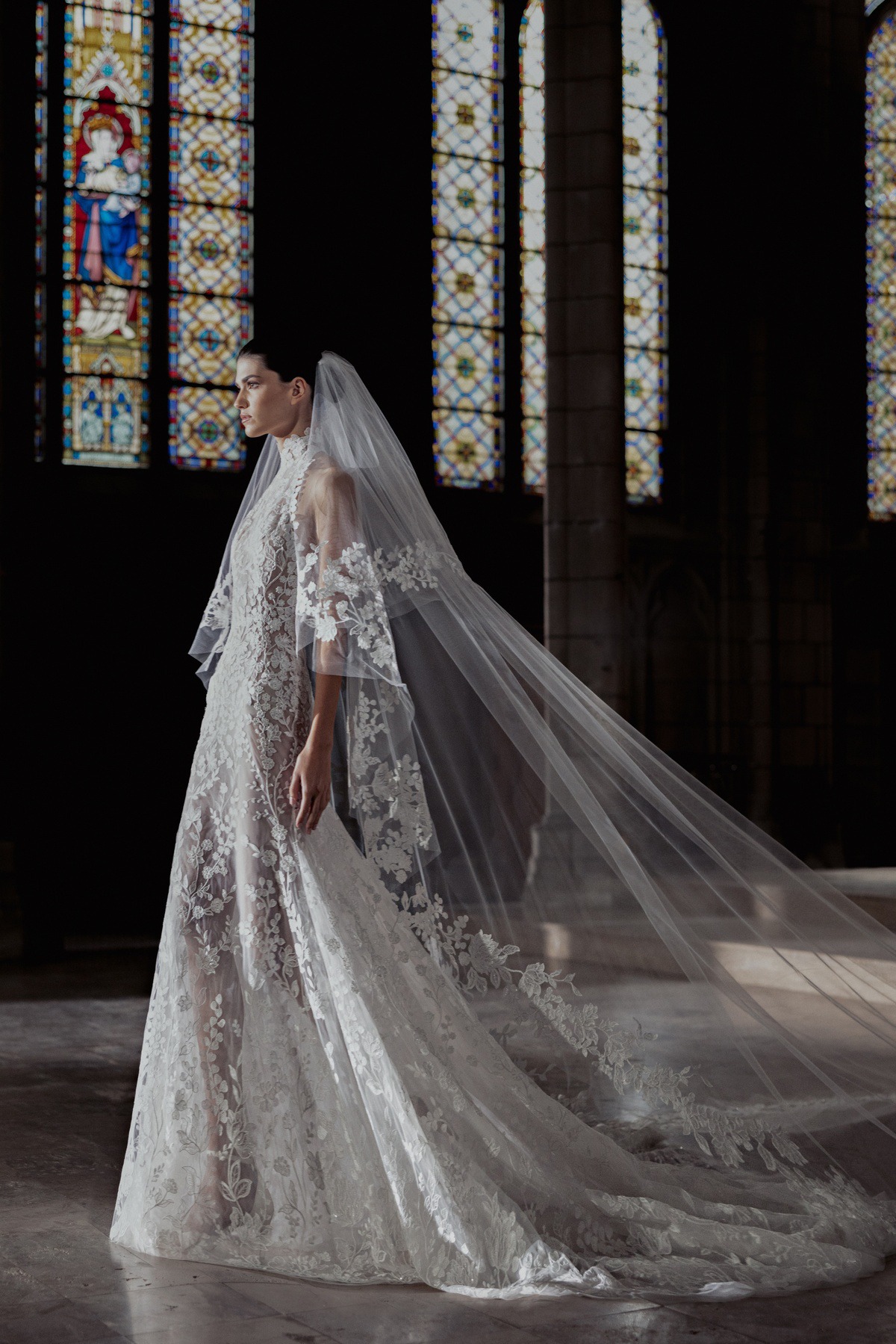 Trouwjurk met kant Hailey van Zuhair Murad. Zijaanzicht van de see-through A-lijn jurk met hoge hals en sluier.