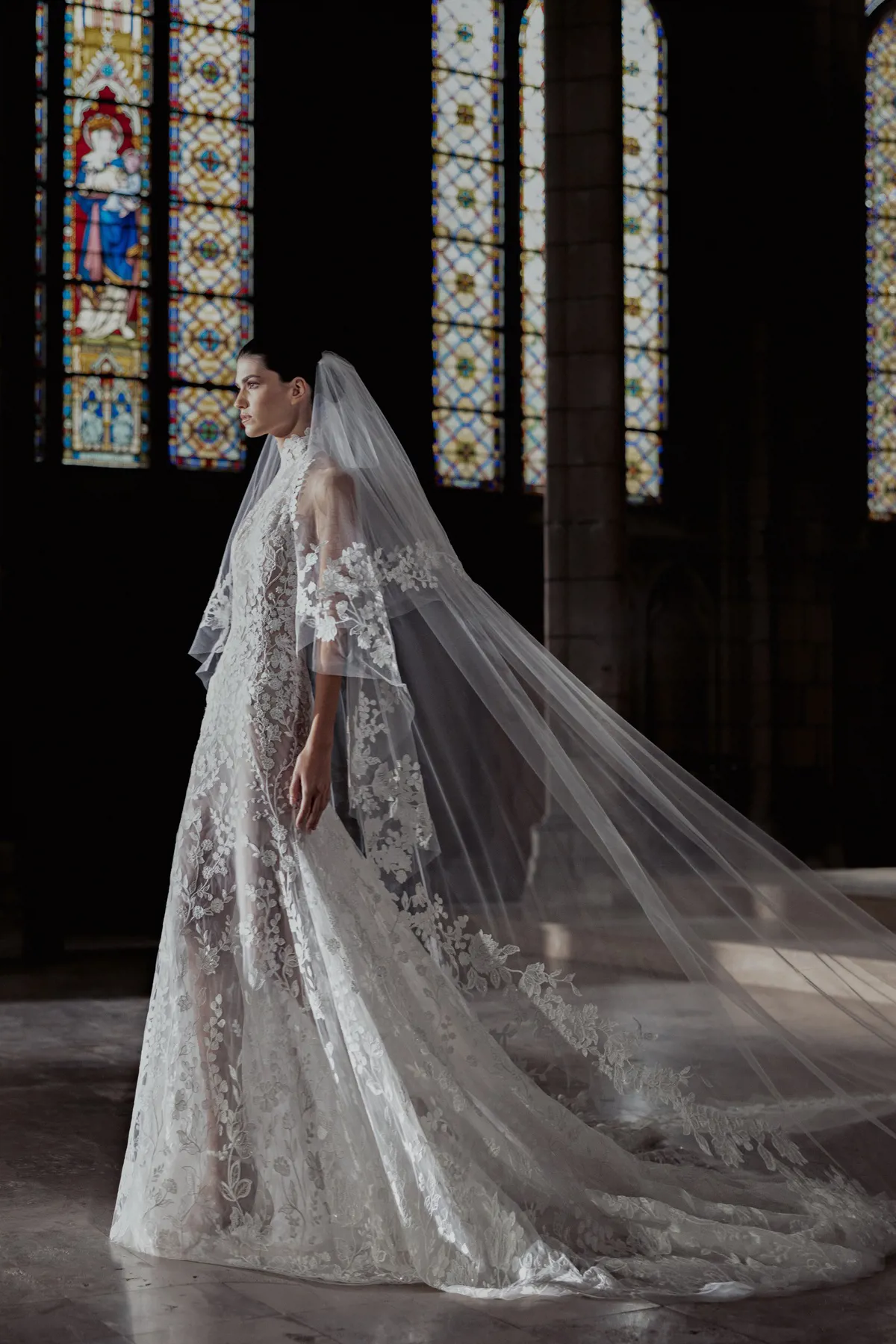 Trouwjurk met kant Hailey van Zuhair Murad. Zijaanzicht van de see-through A-lijn jurk met hoge hals en sluier.
