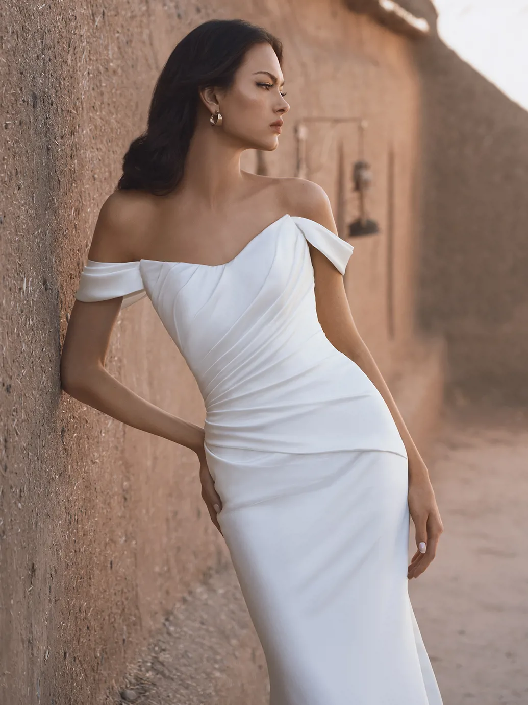 Off-shoulder trouwjurk Thu van Blue by Enzoani. Zijaanzicht van de aangesloten satijnen jurk met gedrapeerd lijfje.
