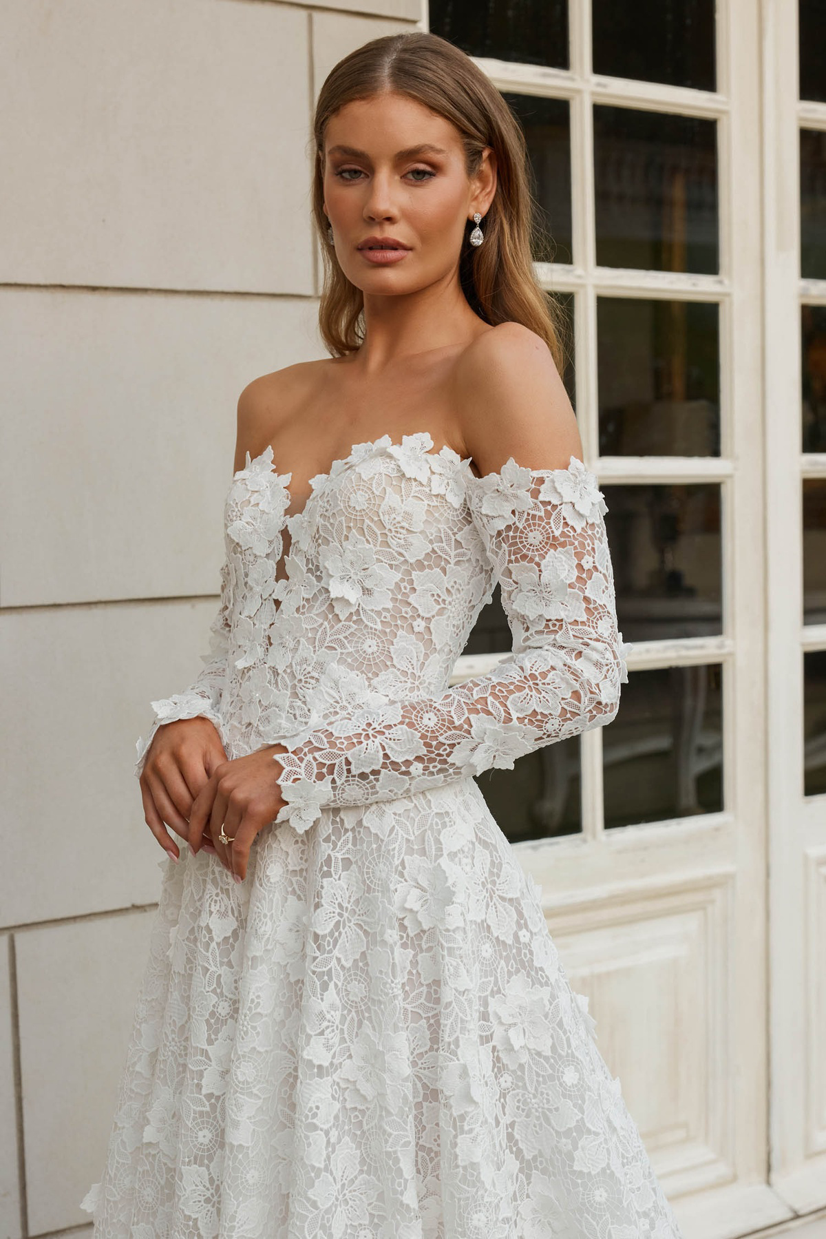 Off-shoulder trouwjurk Salem met 3D kant en lange mouwen van Jeune by Madi Lane. Close-up van het romantische lijfje.