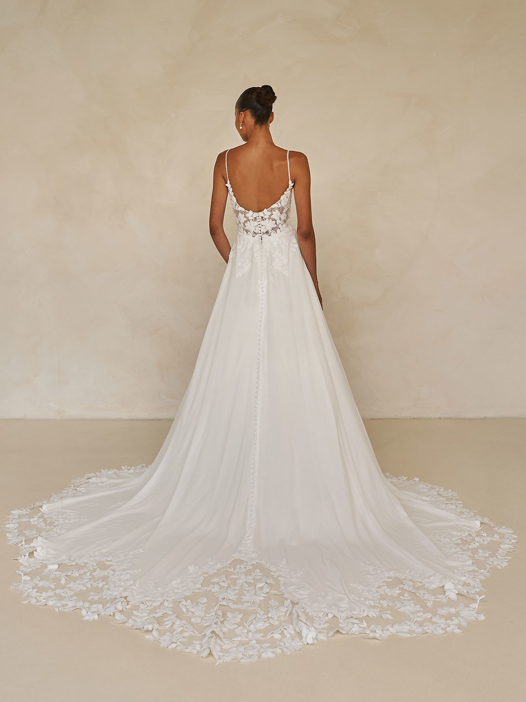 Trouwjurk Whyte van Madi Lane met lage rug, achteraanzicht. A-lijn bruidsjurk met een lange sleep met 3D kant applicaties.