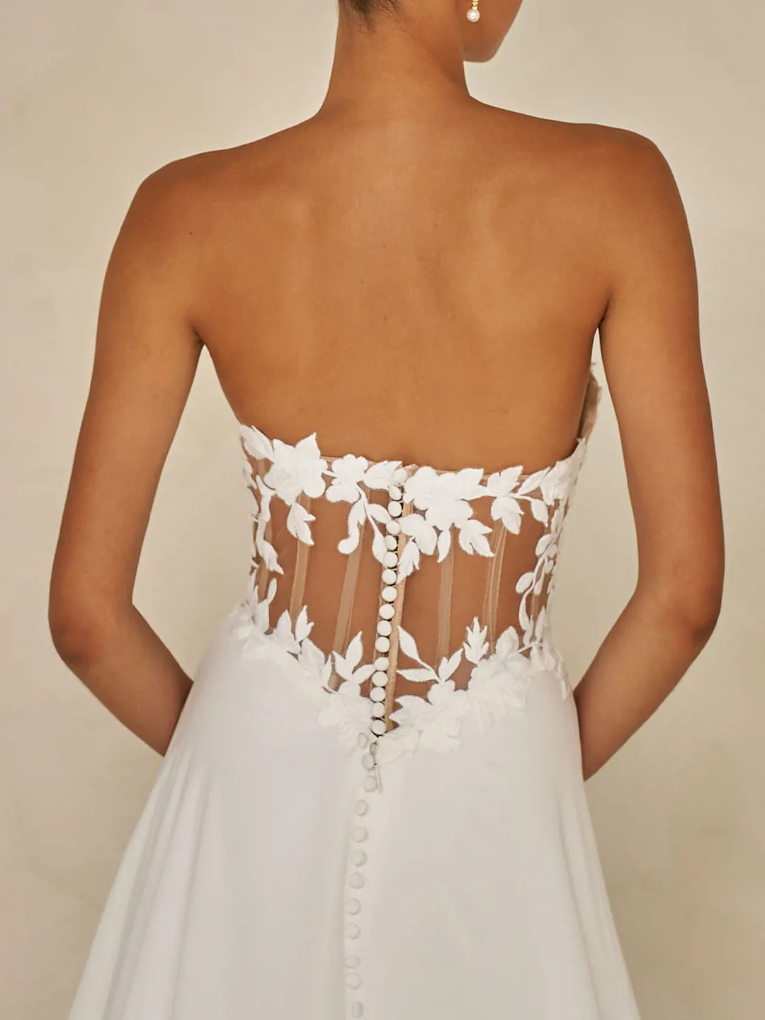 Trouwjurk Wynne van Madi Lane, achteraanzicht met see-through korsetlijfje, bloemenkant en een rij picpac knoopjes.
