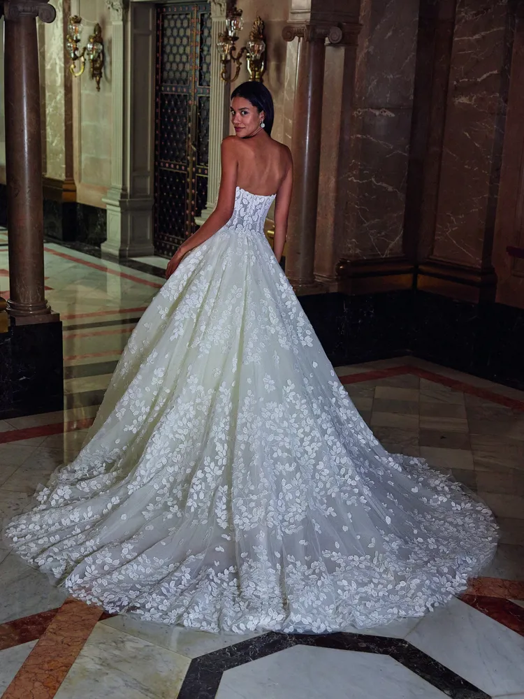 Prinsessenjurk DP546 van Demetrios Platinum. Achteraanzicht van de strapless trouwjurk met bladapplicaties en lange sleep.