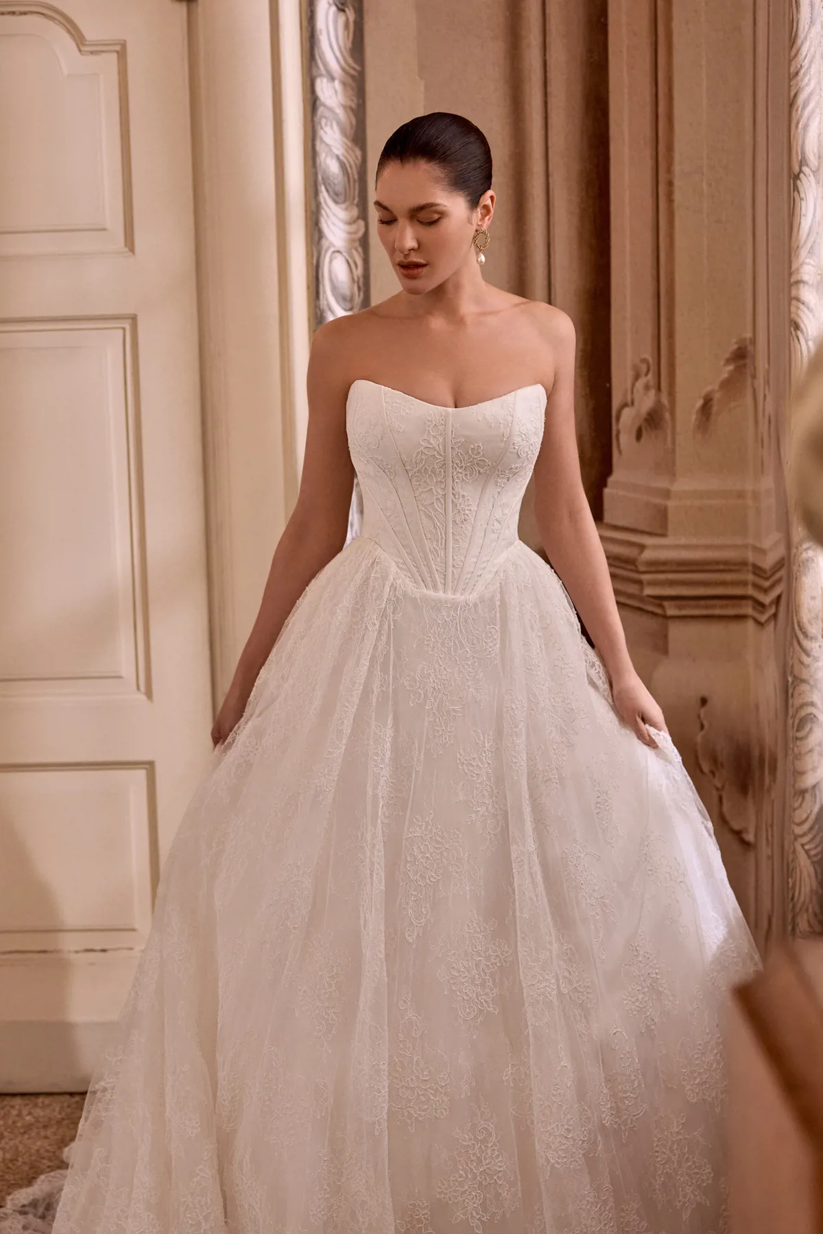 Trouwjurk met korset Leight van Pronovias. Vooraanzicht van de strapless prinsessenjurk met een volle rok van kant.