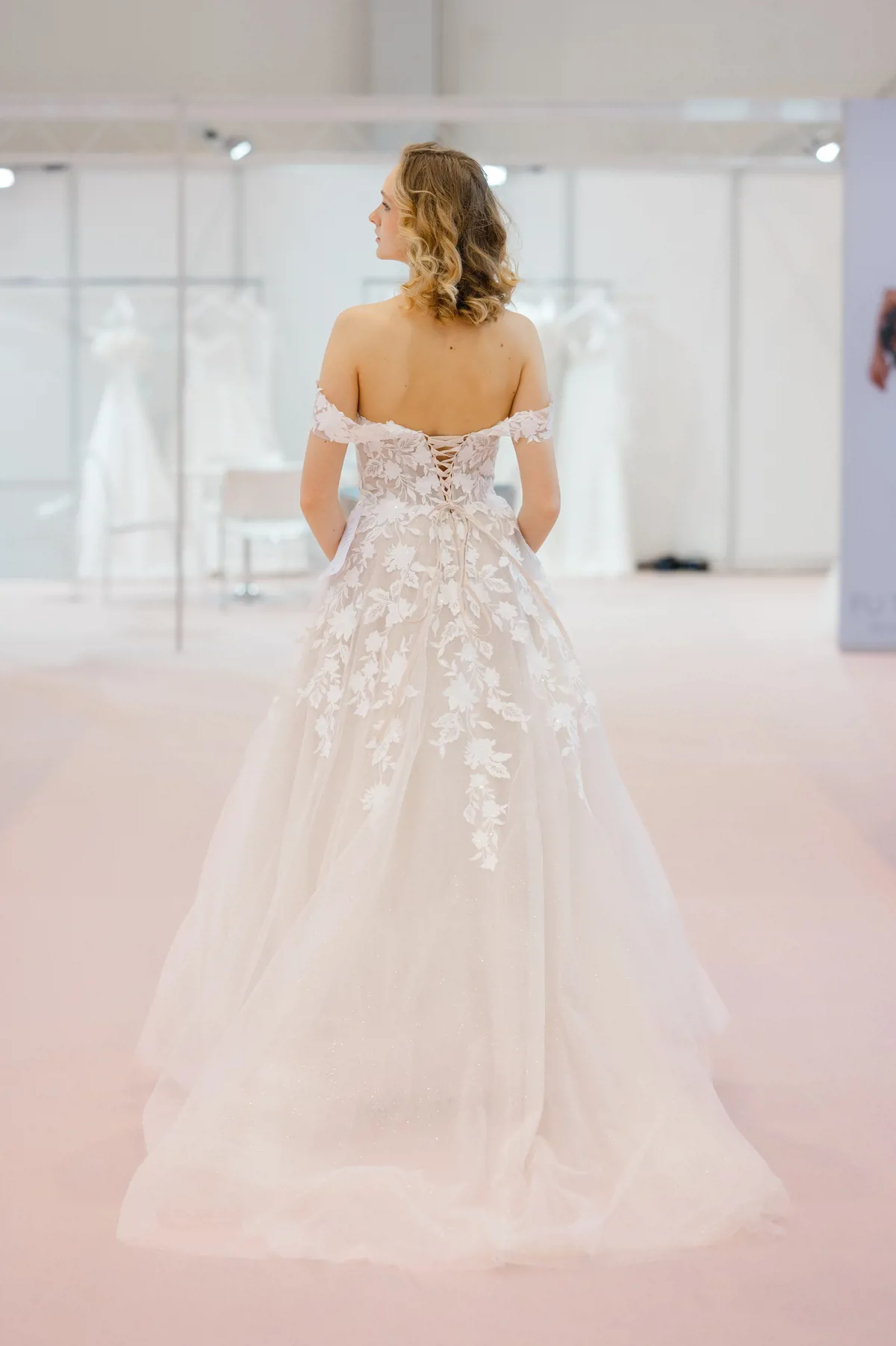 Off-shoulder A-lijn trouwjurk Deena van Azuree. Achteraanzicht met kanten korsetlijfje en een romantische glitter tule rok.