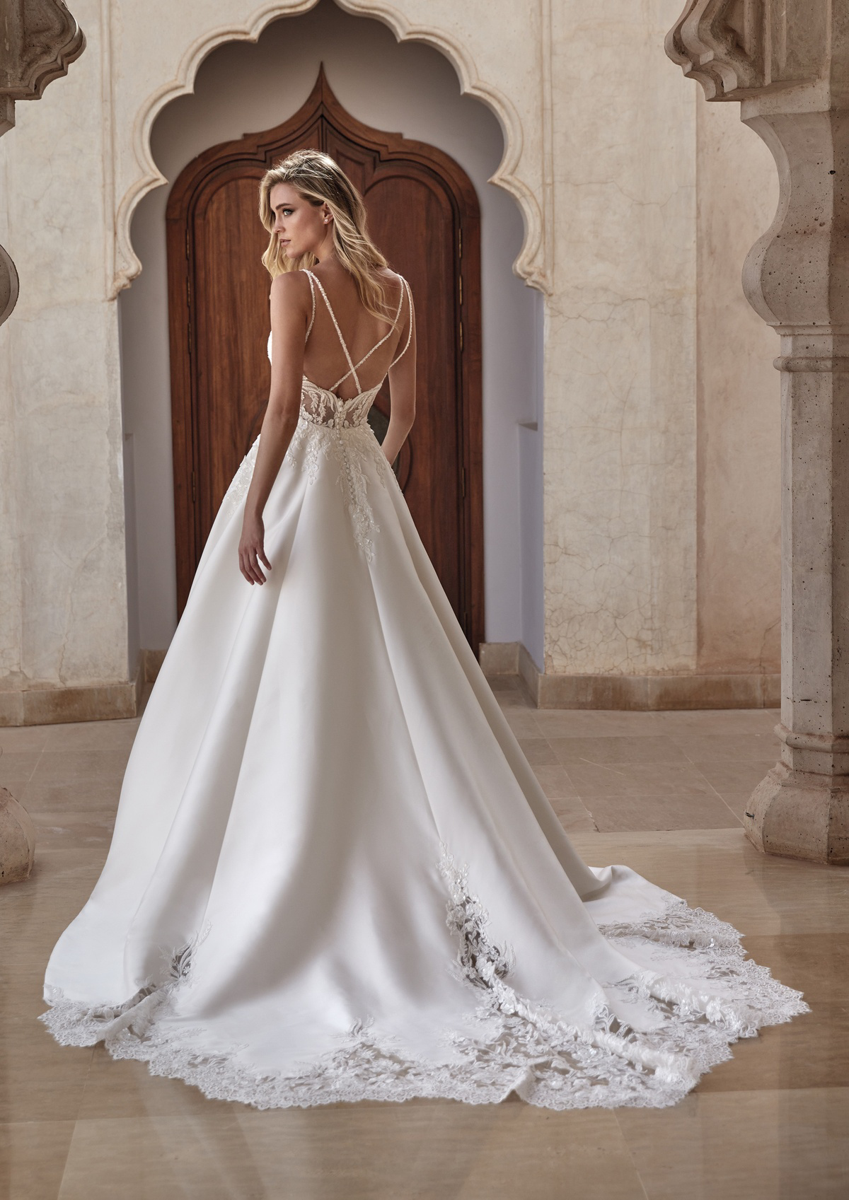 Satijnen A-lijn trouwjurk Misti van Pronovias met lage rug en kanten sleep. Achteraanzicht met gekruiste spaghettibandjes.