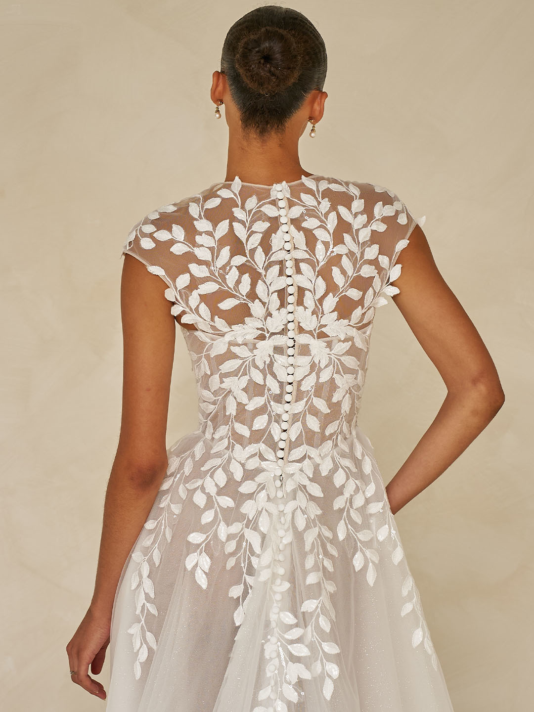 Trouwjurk Whitley van Madi Lane, achteraanzicht van de see-through rug met bladapplicaties en subtiele picpac knoopjes.