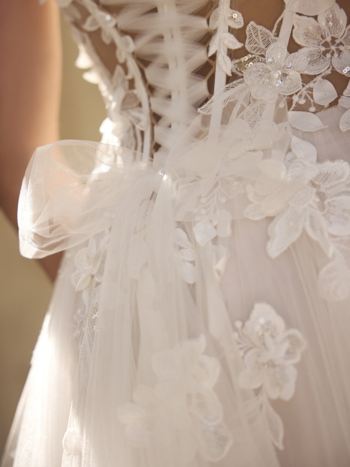 Bruidsjurk Galaxy van Modeca met 3D kant. Close-up achteraanzicht van het romantische korsetlijfje met tule strik.