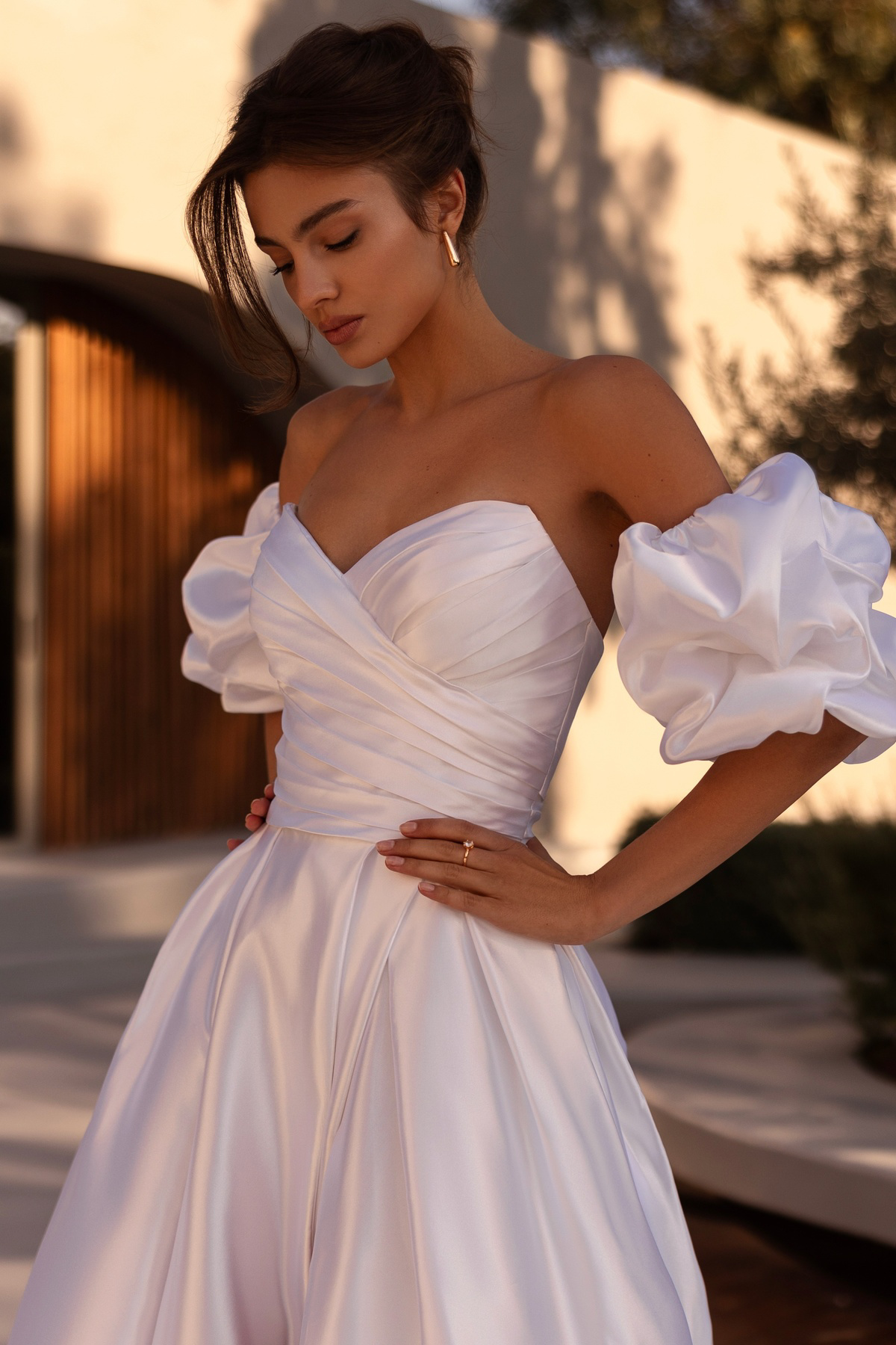 A-lijn trouwjurk 1525 Demetrios. Close-up van het satijnen gedrapeerde lijfje en opvallende off-shoulder pofmouwen.