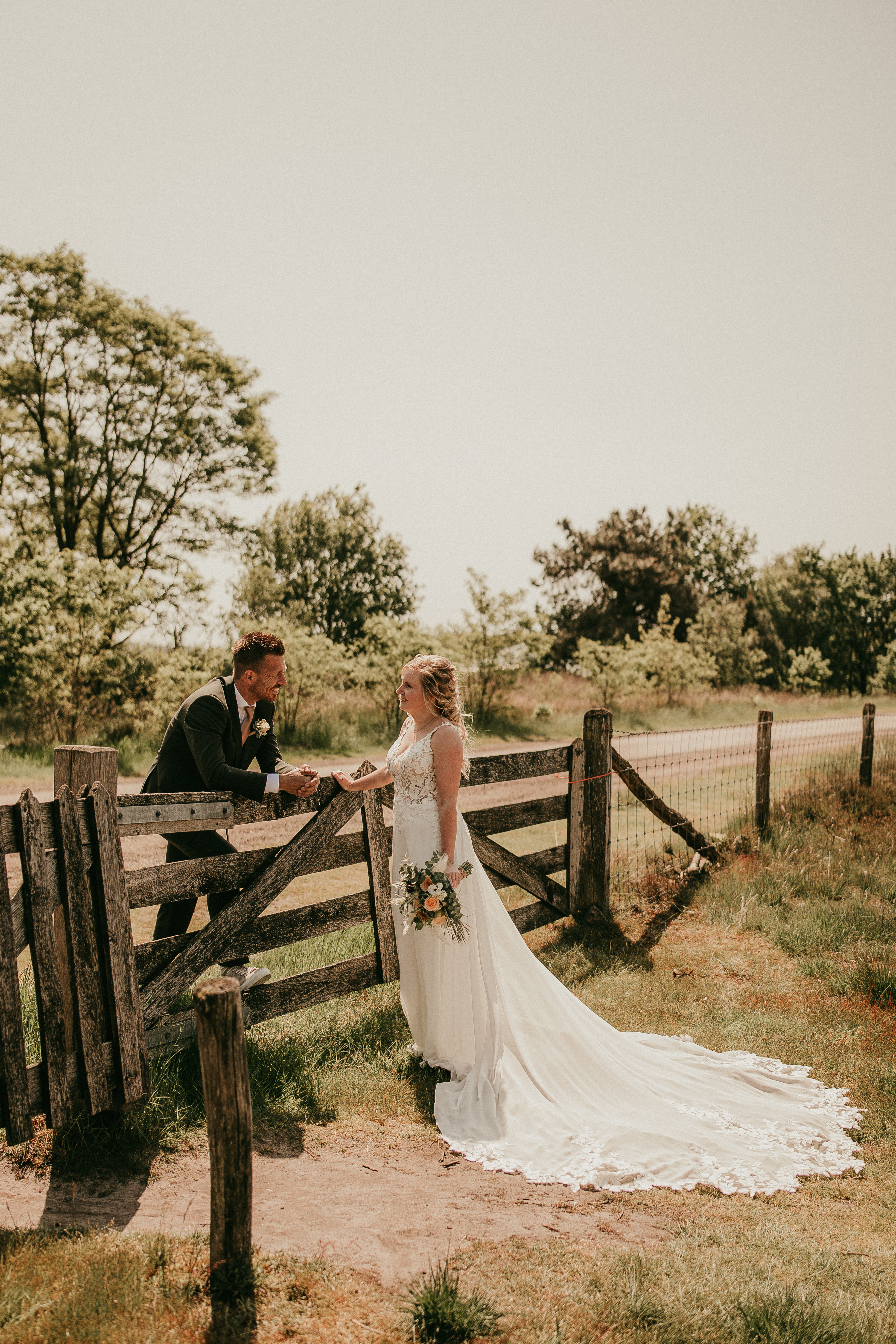 rianne in trouwjurk bij een hek