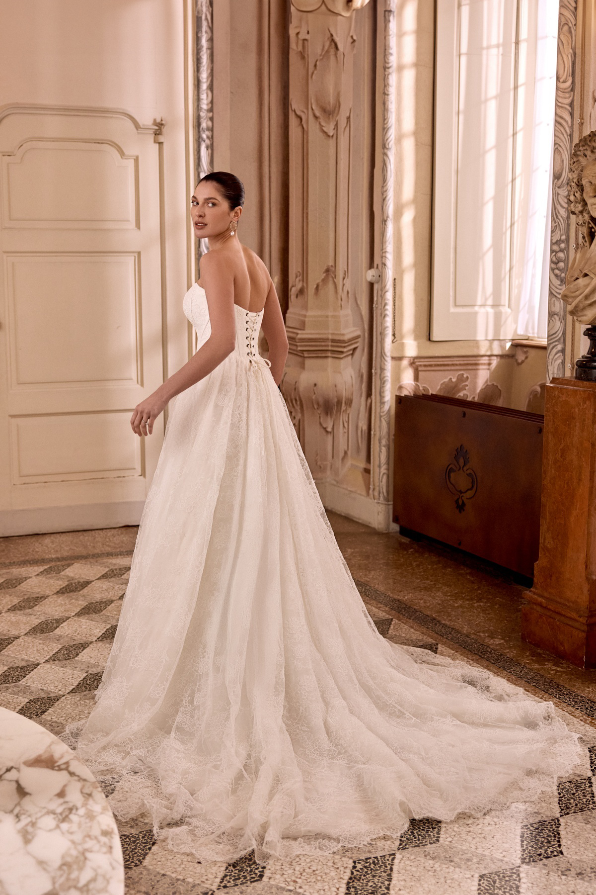 A-lijn trouwjurk Leight van Pronovias, achteraanzicht. Strapless bruidsjurk met romantisch korsetlijfje en lange kanten sleep.