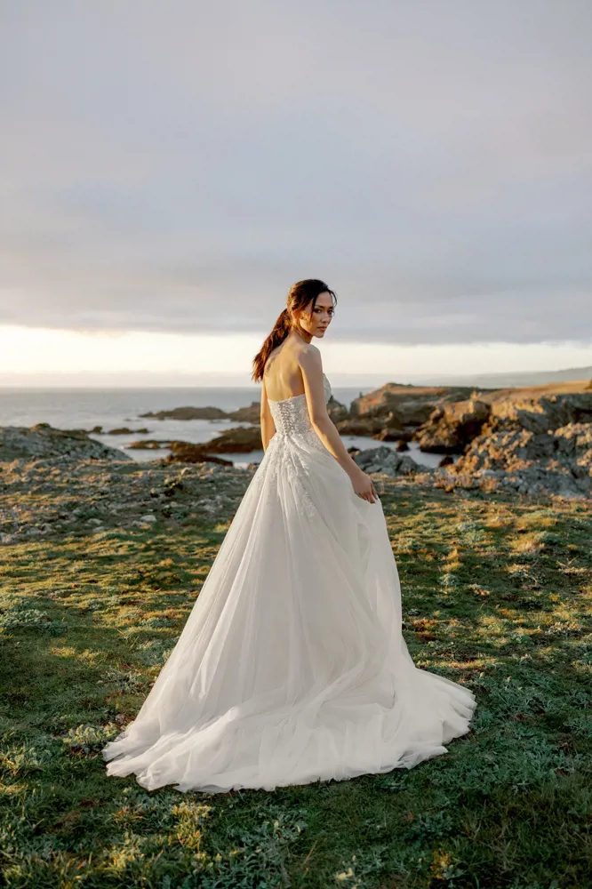 Strapless A-lijn trouwjurk 11424 van Adore met kanten korsetlijfje en een flowy tule rok, achteraanzicht in de natuur.