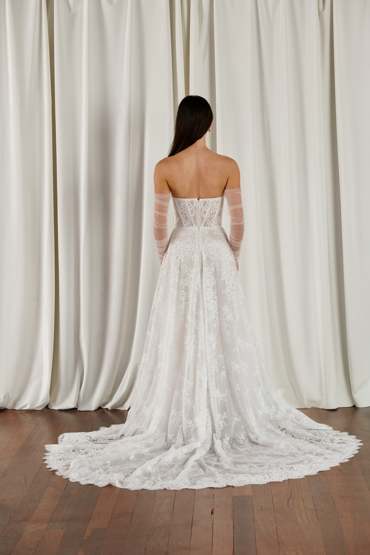 Strapless A-lijn trouwjurk 23203 van Cizzy Bridal. Achteraanzicht van de kanten jurk met losse mouwen en lange sleep.