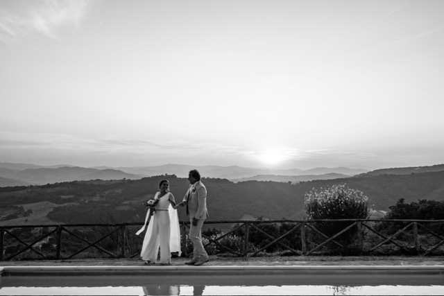 real-bride-review-daphne-de-laat-bruidshuis-diana – bruid Daphne de Laat en haar bruidegom wandelen hand in hand met uitzicht over een berglandschap bij zonsondergang