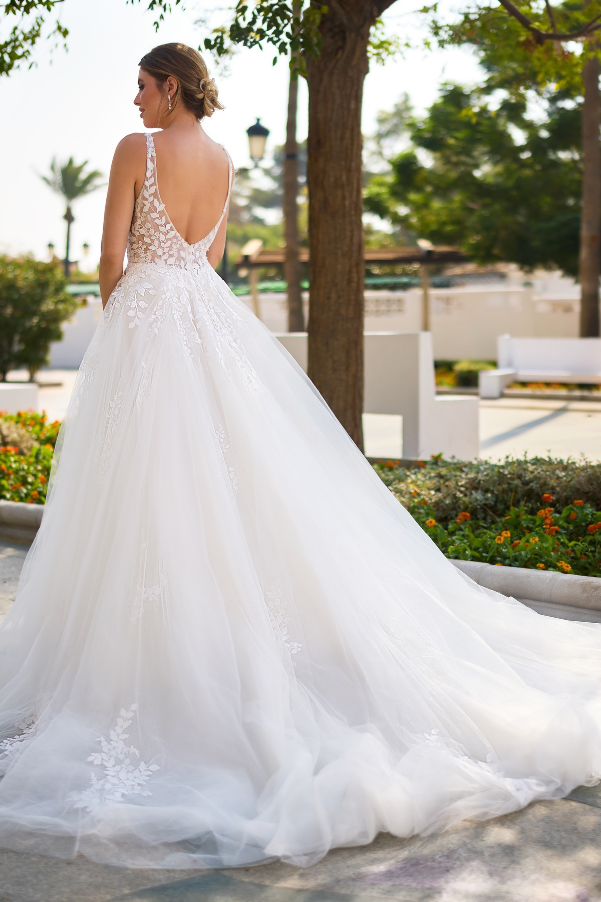 A-lijn trouwjurk 26222 van Tres chic met lage rug. Achteraanzicht van het kanten lijfje en de wijde tule rok met lange sleep.