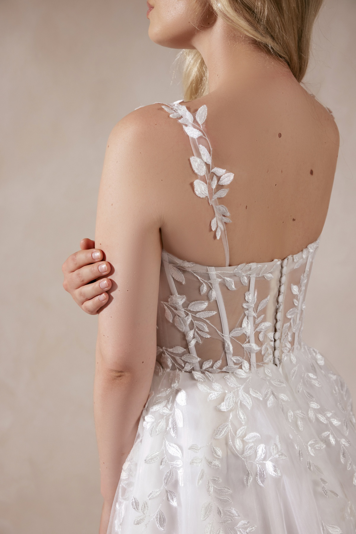 Korset trouwjurk Seraphina van Adore. Achteraanzicht van het see-through lijfje met baleinen en kanten blad applicaties.