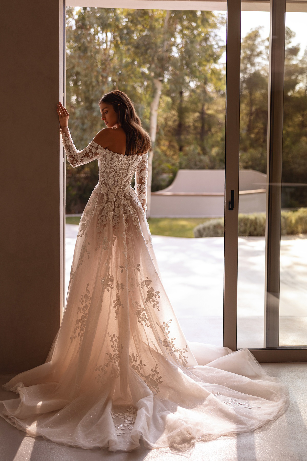 Off-shoulder trouwjurk 1502 Demetrios met lange kanten mouwen. Achteraanzicht van de A-lijn jurk met subtiele glitters.