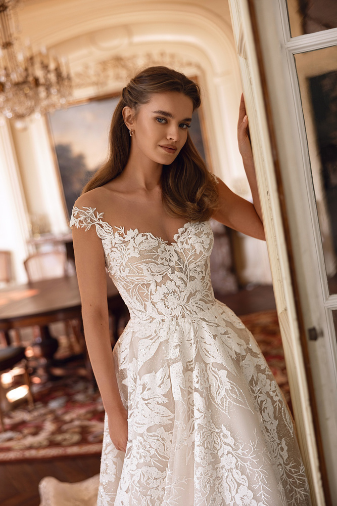 A-lijn trouwjurk met kant Jianna van Oliver Martino. Vooraanzicht met off-shoulder kapmouwtjes en een see-through lijfje.