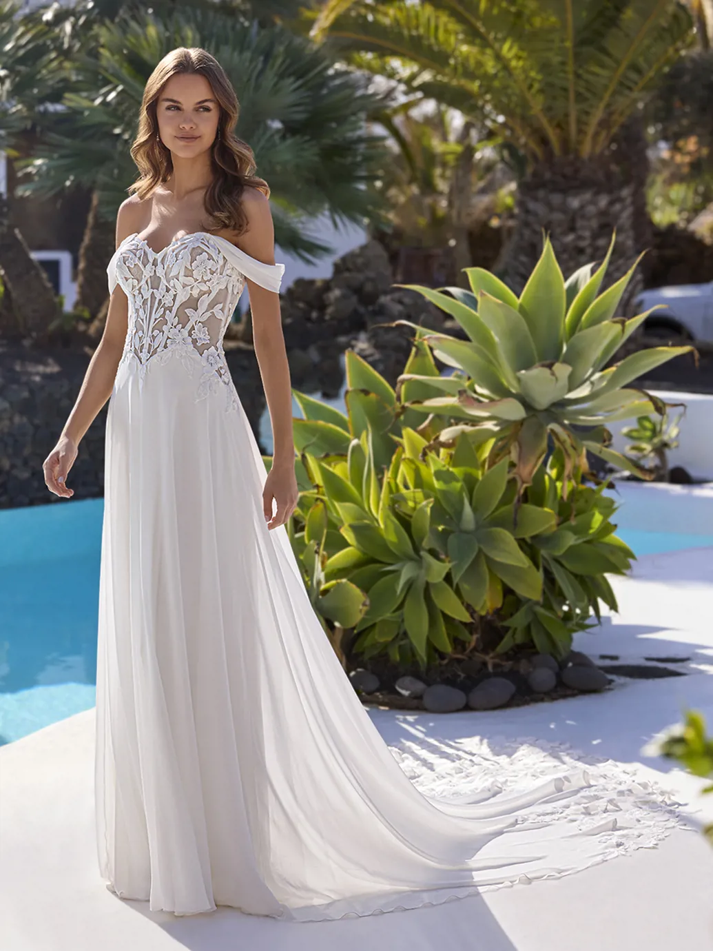A-lijn trouwjurk Elsa van Love by Enzoani met off-shoulder bandjes en een kanten see-through lijfje. Vooraanzicht.