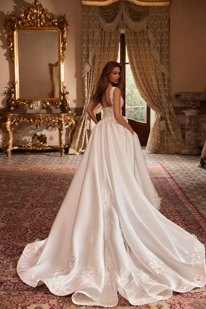 Bruidsjurk met lage rug Tia van Blue by Enzoani. Achteraanzicht van de A-lijn jurk met satijnen rok en kanten sleep.