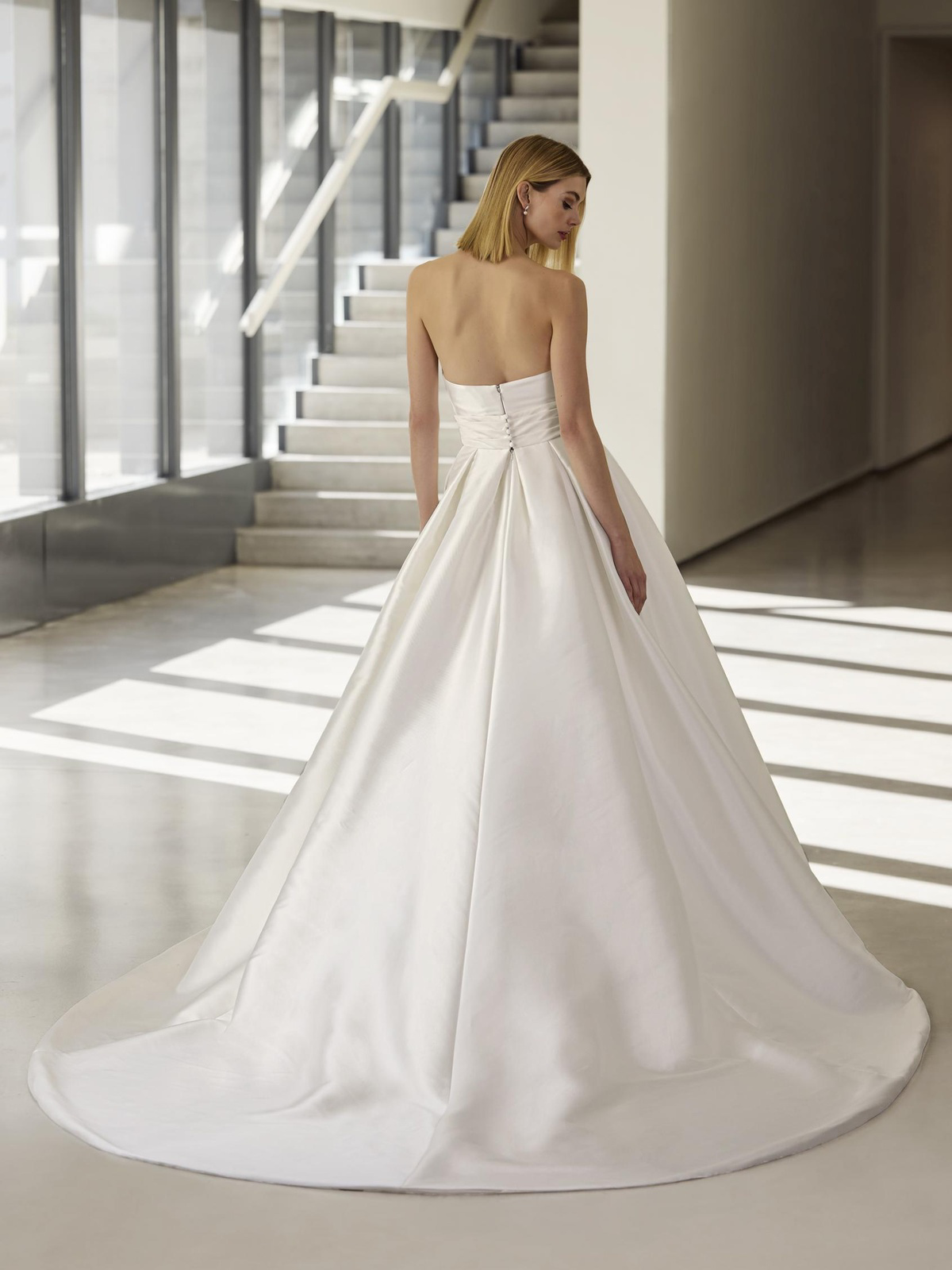 A-lijn trouwjurk Leaves van Pronovias. Achteraanzicht van de strapless satijnen jurk met open rug en picpac knoopjes.