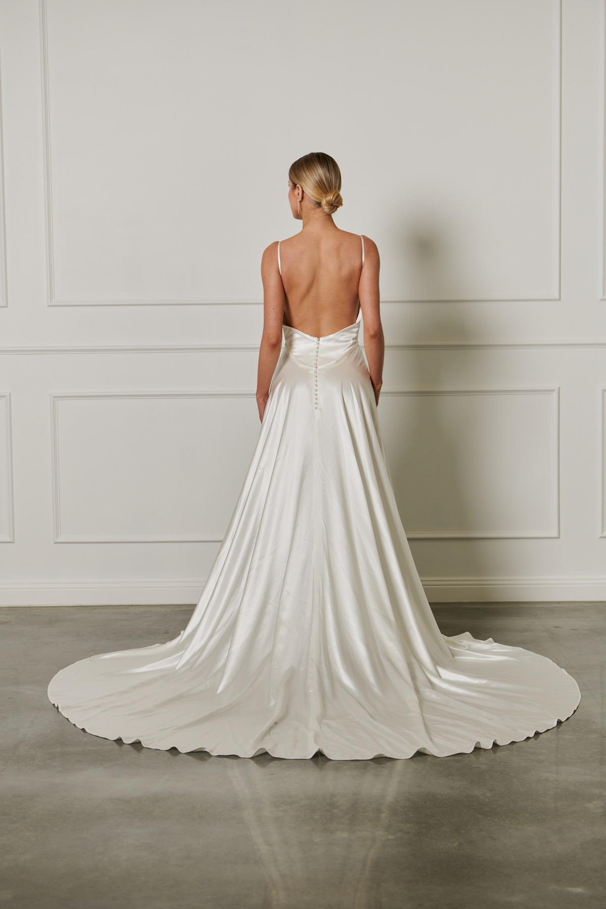 Trouwjurk met lage rug 23207 van Cizzy Bridal. Achteraanzicht van de satijnen A-lijn jurk met picpac knoopjes.