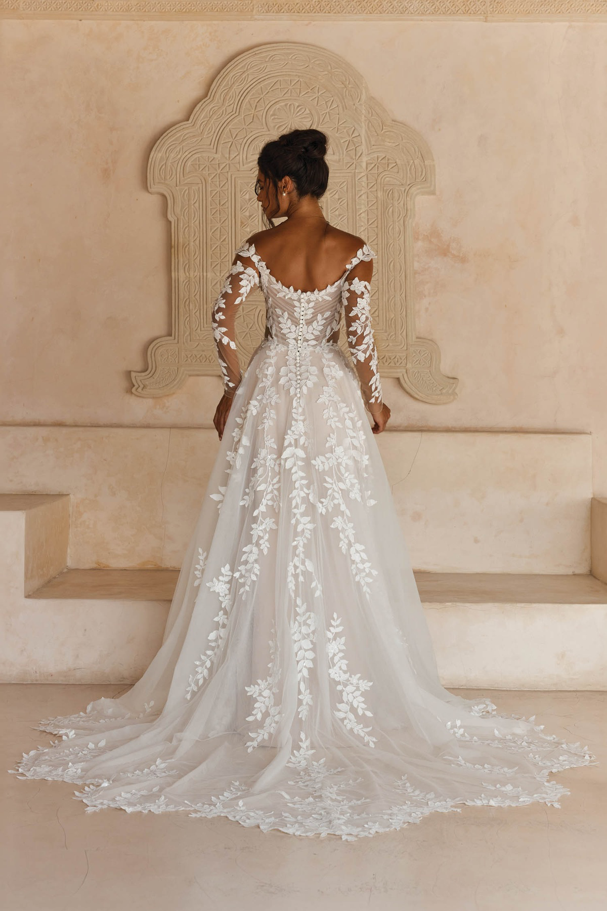 Trouwjurk met lange mouwen Landon van Madi Lane. Achteraanzicht van de A-lijn jurk met lage rug en botanisch kant.