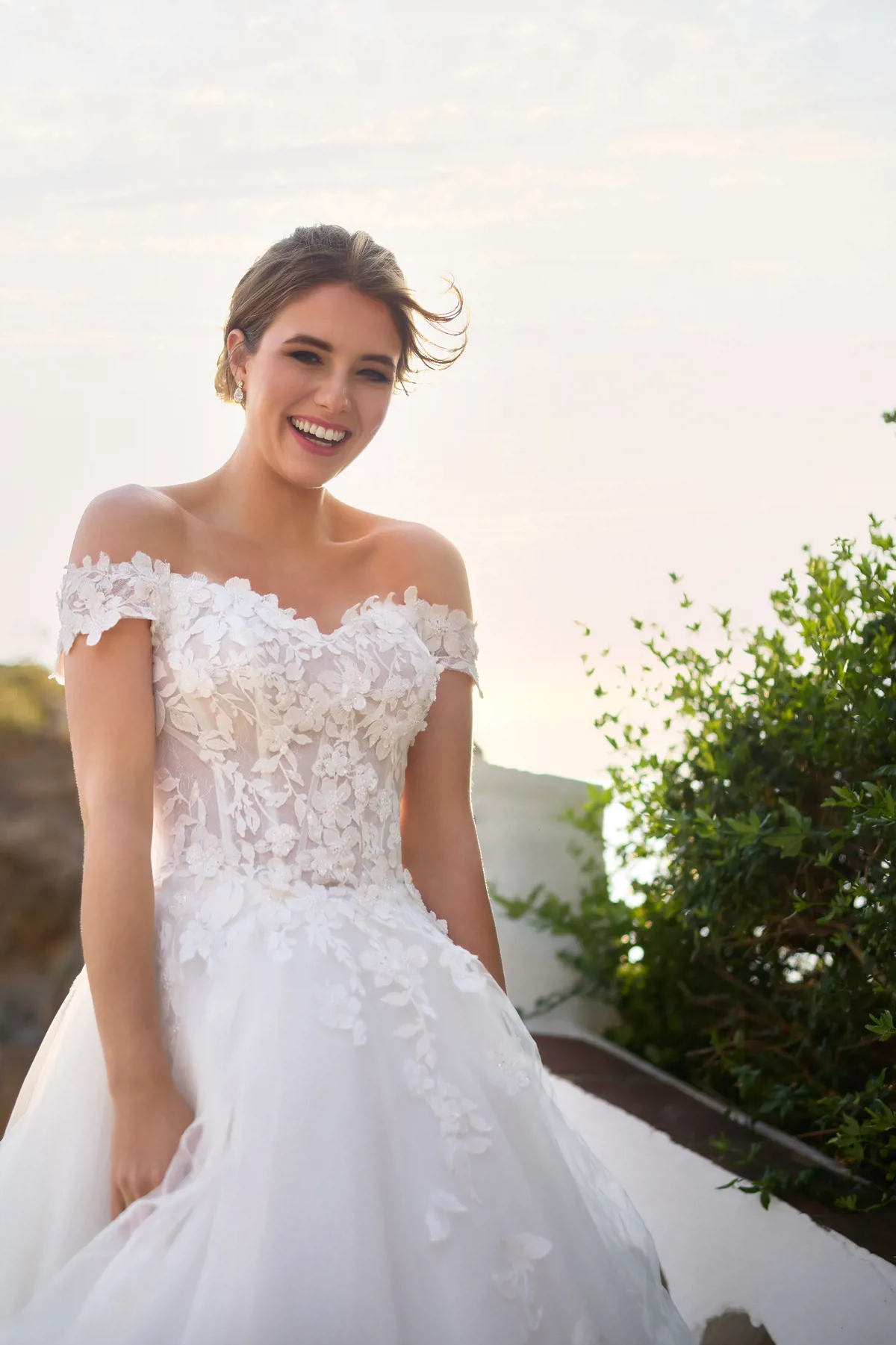 Off-shoulder trouwjurk 26206 van Tres chic met 3D kant en een see-through korsetlijfje. Close-up van lachende bruid.