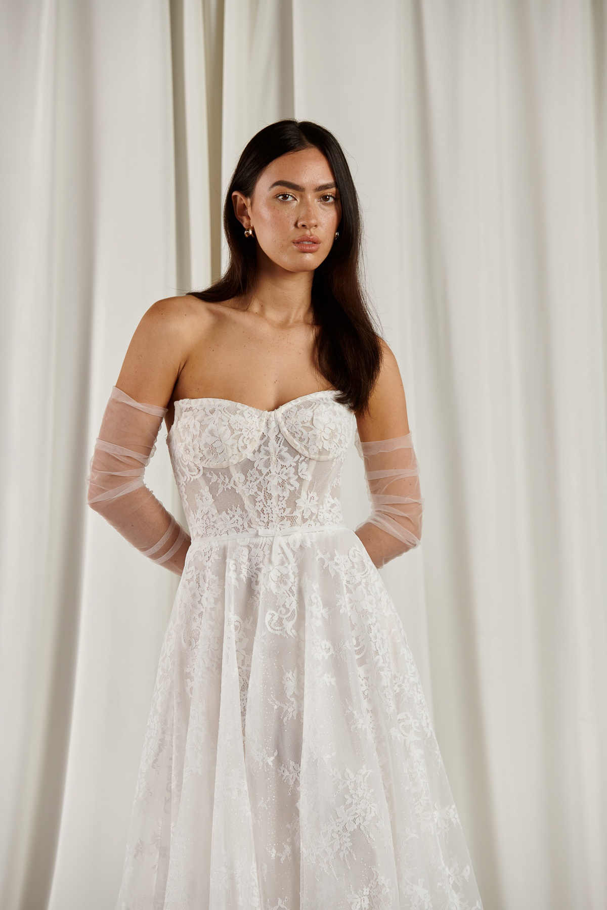 Kanten A-lijn trouwjurk 23203 van Cizzy Bridal. Vooraanzicht met strapless korsetlijfje en losse tule mouwen.