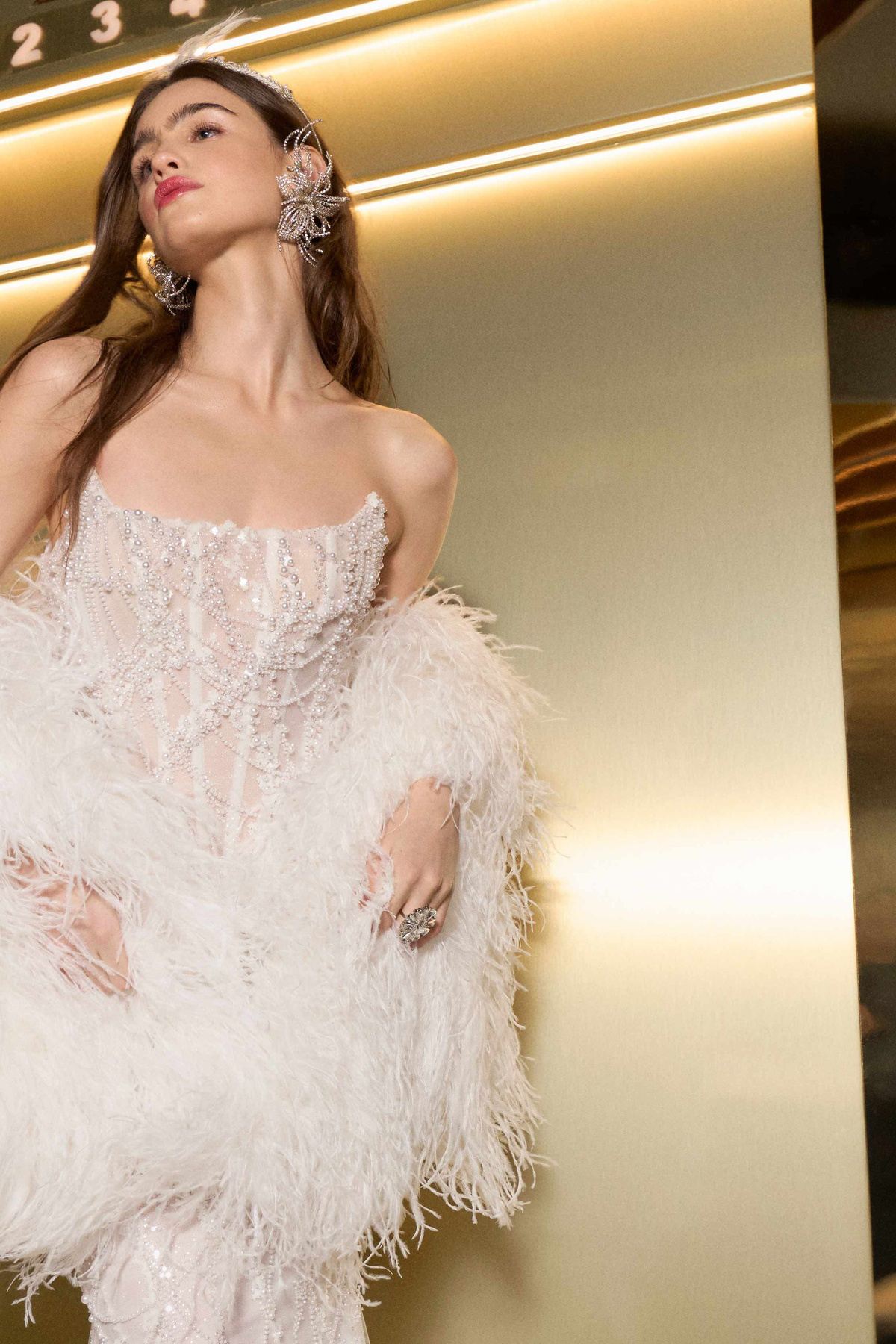 Luxe trouwjurk Gatsby van Galia Lahav. Close-up van het see-through korsetlijfje met parels en een veren stola.