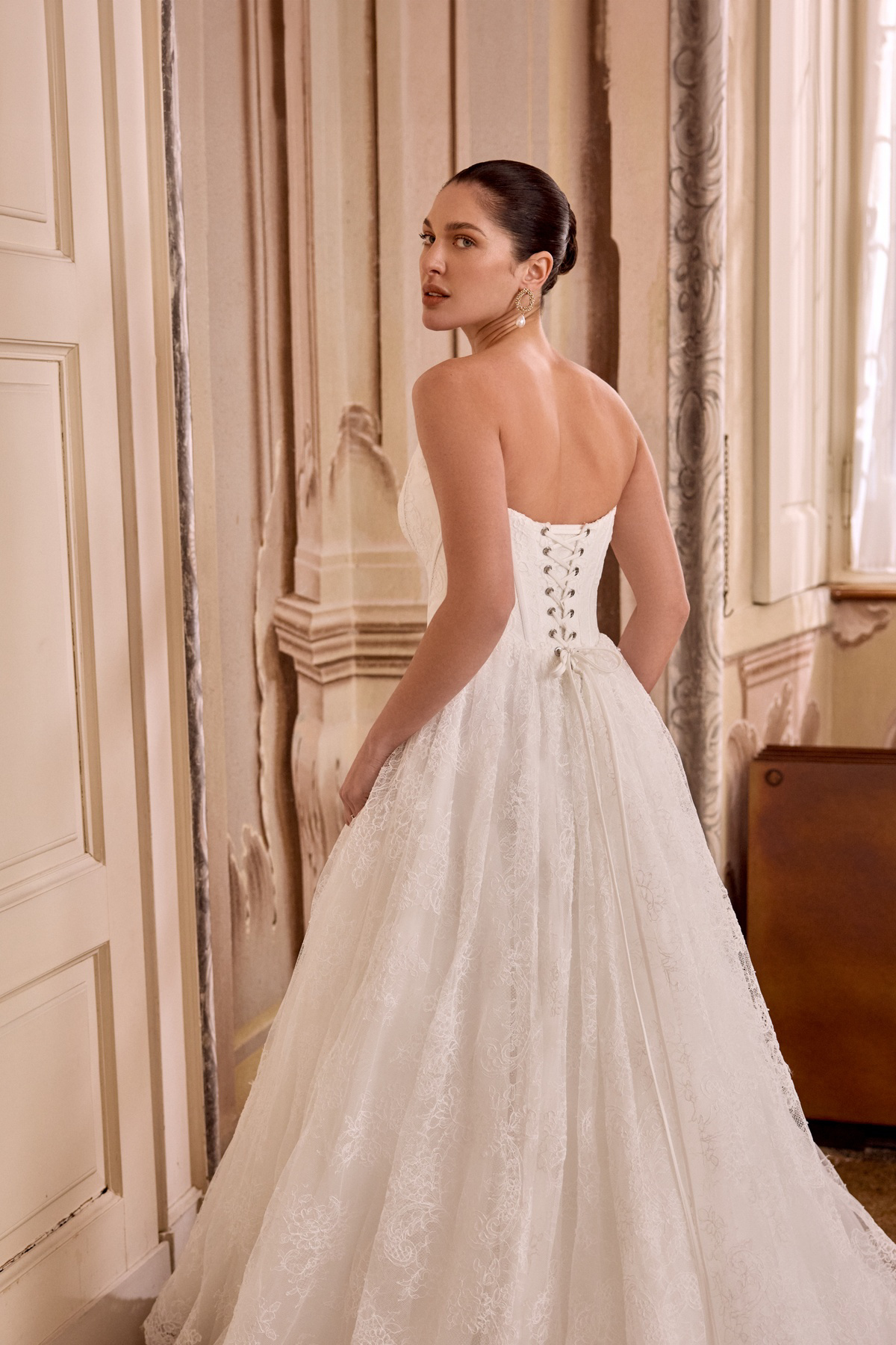 Bruidsjurk met korset Leight van Pronovias. Achteraanzicht van de strapless A-lijn trouwjurk met een rok van volledig kant.