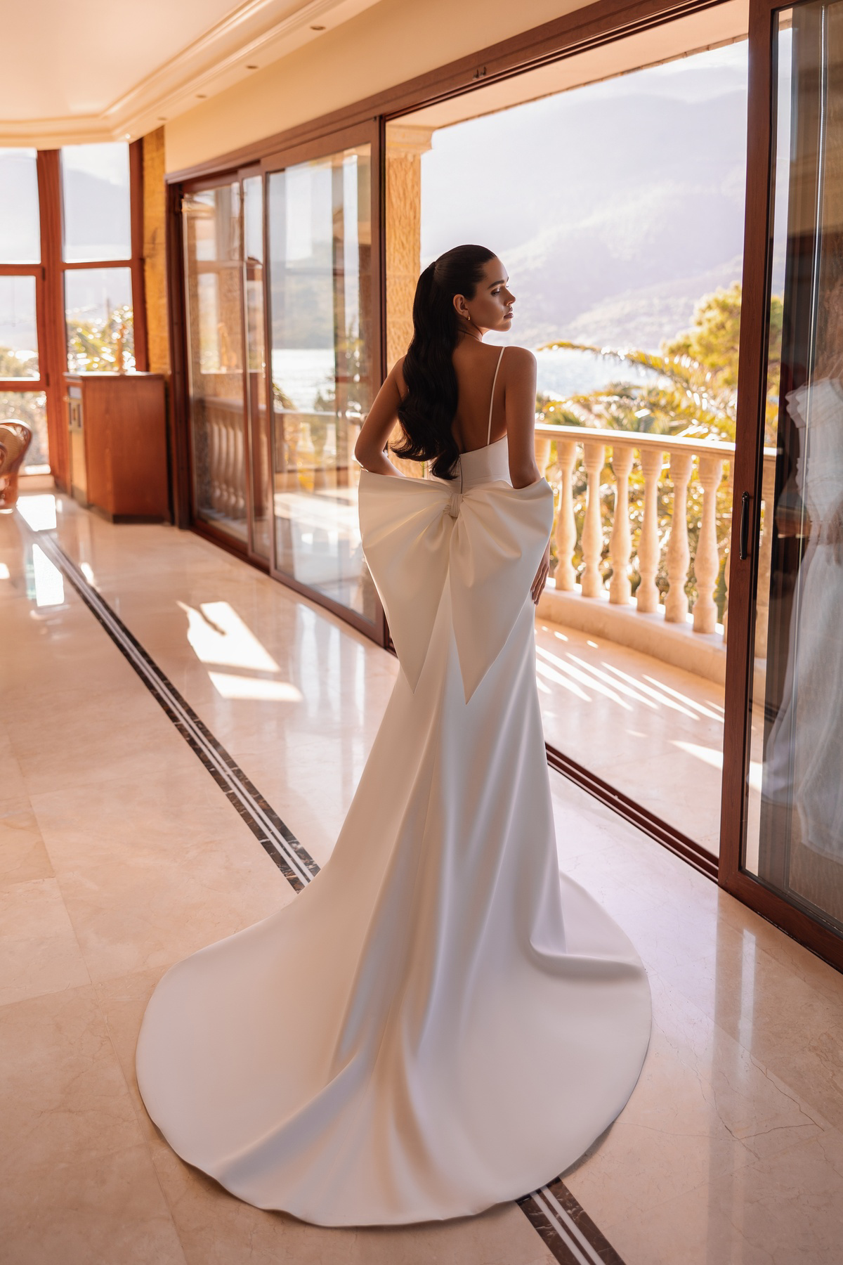 Trouwjurk met lage rug 8250 van Cosmobella met een grote strik. Achteraanzicht van de aangesloten, satijnen bruidsjurk.