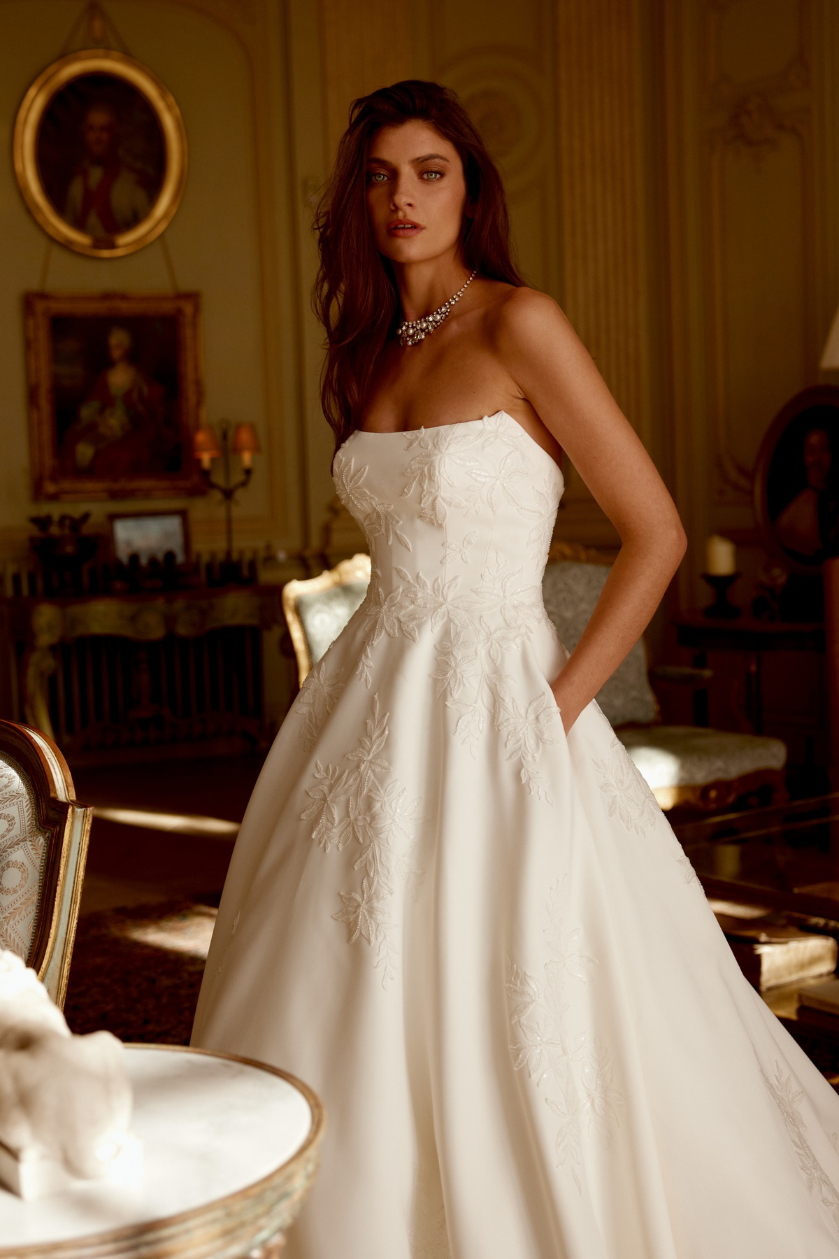 A-lijn trouwjurk Jordan van Justin Alexander. Zijaanzicht van de strapless jurk met geborduurde bloemen en zakken.