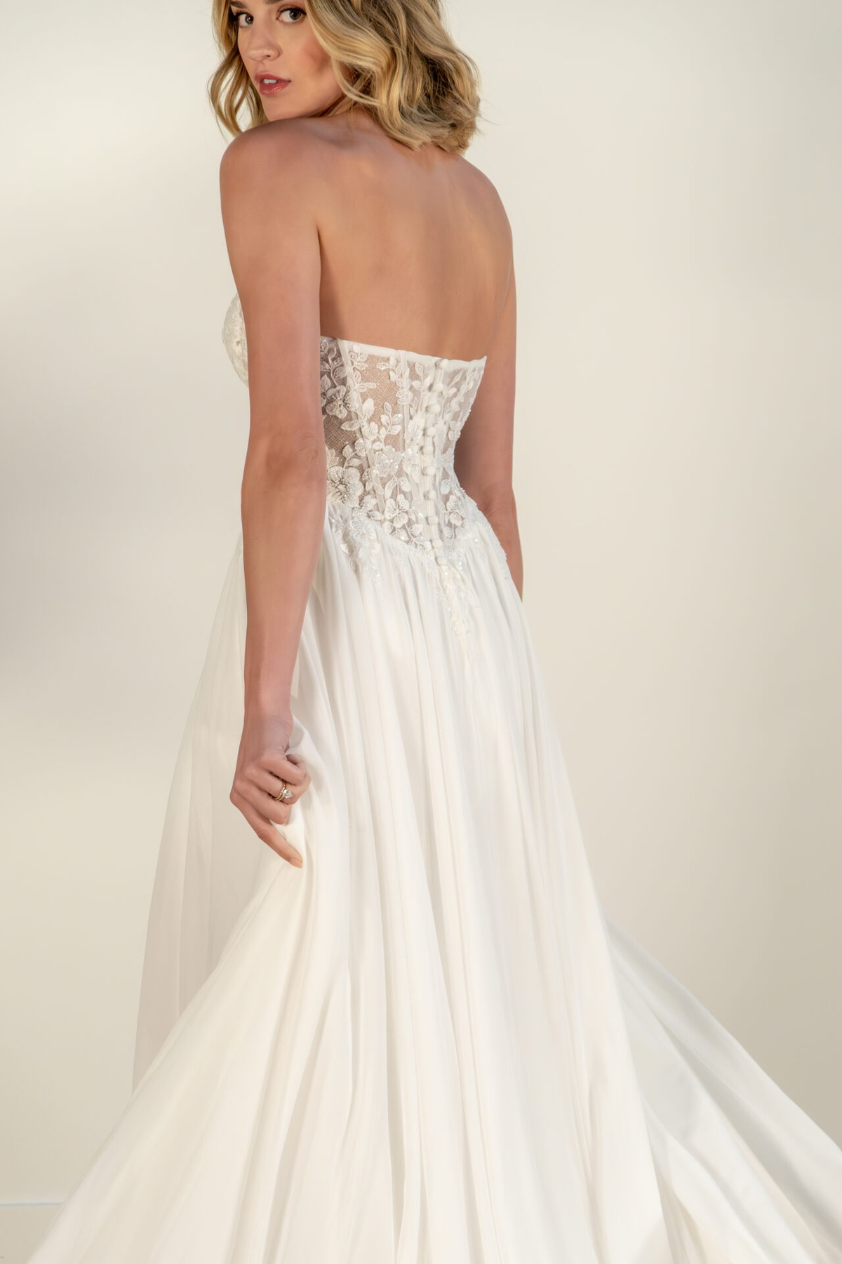 Trouwjurk Stella York 8027 achteraanzicht. Strapless model met see-through kanten lijfje en flowy rok.