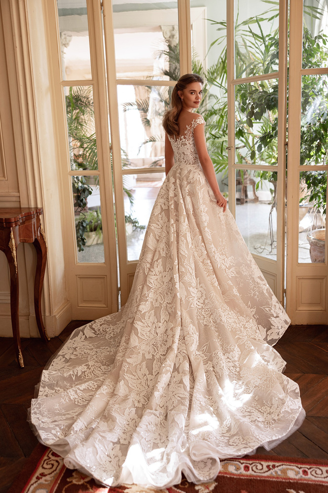 A-lijn trouwjurk Jianna van Oliver Martino met bloemenkant. Achteraanzicht van de jurk met kapmouwtjes en lange sleep.