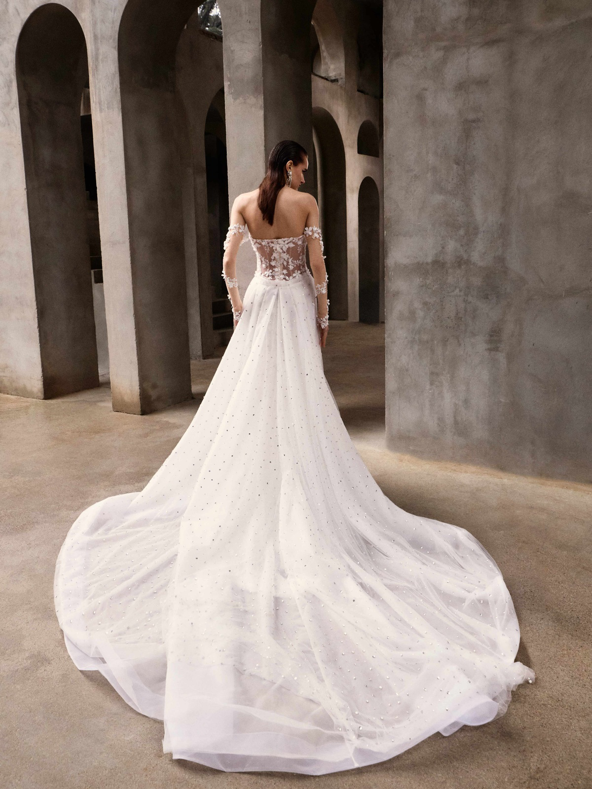 Off-shoulder trouwjurk Lilith van Galia Lahav. Achteraanzicht met een see-through kanten rug en een lange glitter tule sleep.