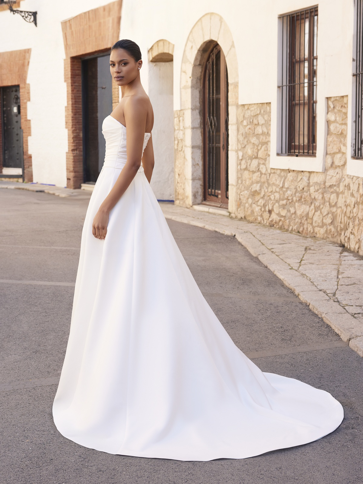 Strapless A-lijn trouwjurk Easthar van White one. Zijaanzicht van de minimalistische jurk met gedrapeerd lijfje en sleep.