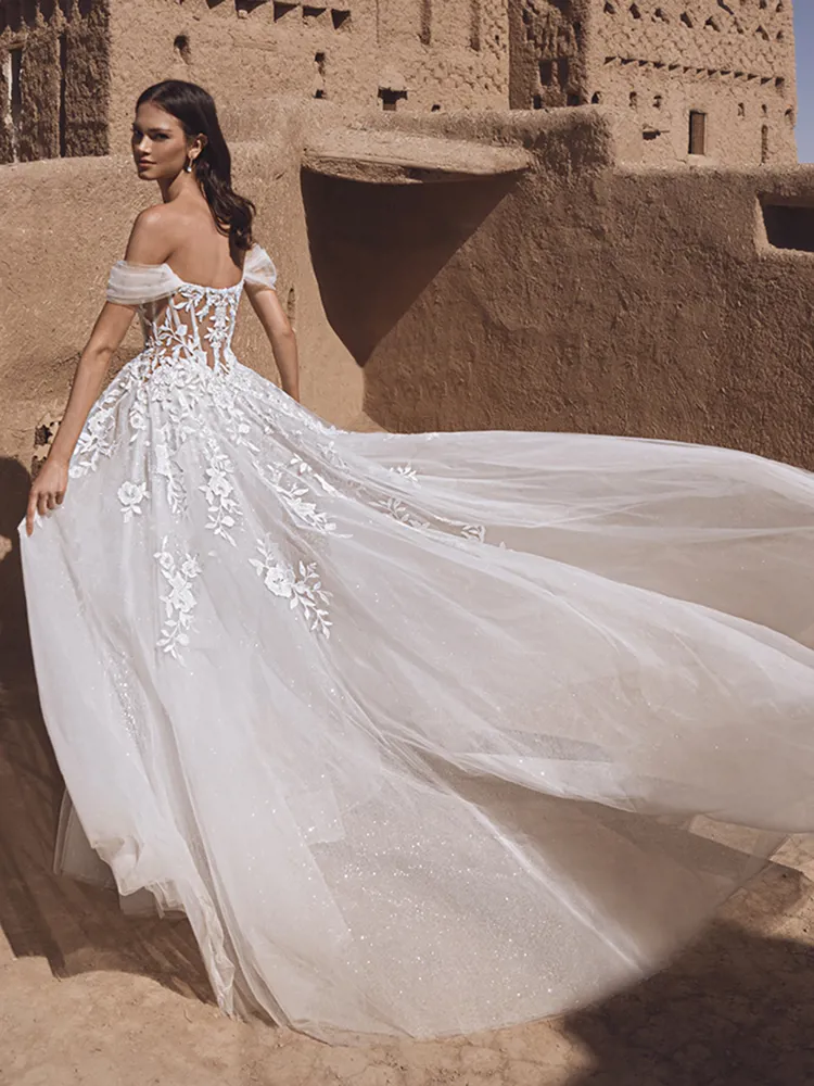 A-lijn trouwjurk Taylee van Blue by Enzoani met off-shoulder bandjes. Achteraanzicht van het see-through korset en glitter tule.