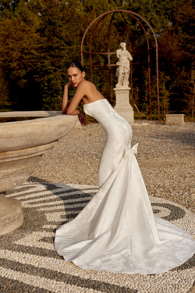 Zeemeermin trouwjurk Kirsten van Justin Alexander. Zijaanzicht van de strapless jurk met picpac knoopjes en een strik.